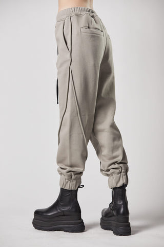 Person trägt ThomKrom WST 384 Pant, eine lässige Sweathose mit elastischem Bündchen und Paspel-Details, kombiniert mit schwarzen Stiefeln. Material aus weicher Baumwoll-Sweat-Qualität.