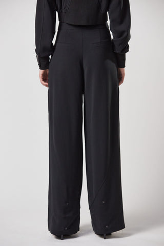 ThomKrom WST390 Pant; Person trägt schwarze, weite Hose mit hoher Taille und umgeschlagenem Saumdetail. Nahaufnahme einer Hand an der Hosentasche zeigt die Stoffstruktur.