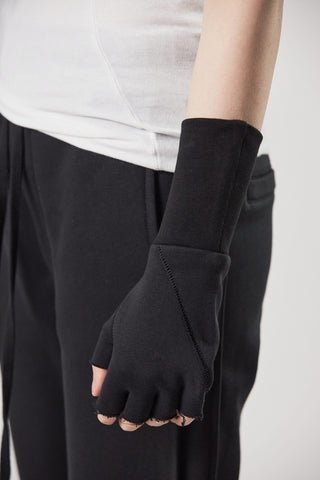 ThomKrom Gloves: Person trägt schwarze Halbfinger-Handschuhe mit tonalen Designnähten und langen Rippenbündchen. Sichtbar sind kleine Taschen und weiches Baumwoll-Sweat-Material.