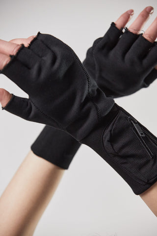 ThomKrom Gloves: Hände tragen schwarze Halbfinger-Handschuhe mit tonalen Designnähten und langen Rippenbündchen. Hergestellt aus weicher Baumwoll-Sweat-Qualität, mit kleinen Taschen integriert.
