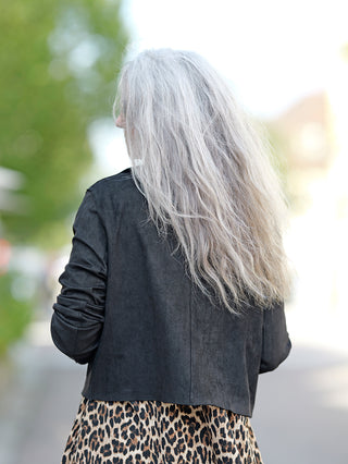 Eine Frau mit langen grauen Haaren trägt die sportliche OFF#DLY Jacke Lena in Velourslederoptik mit seitlichen Taschen und Knopfleiste.