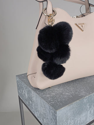 OFF#DLY Taschenanhänger black, ein pinker Plüsch-Pompon-Anhänger aus Polyester, auf einem weißen Untergrund liegend. Perfekt als modisches Accessoire oder Dekoration für Taschen. Größe: 15 x 10 cm.