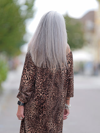 Frau mit grauem Haar trägt das OFF#DLY Dress Alina leo, ein kurzes, schulterfreies Leopardenkleid mit Gummizug am Ausschnitt. Perfekt für Größen bis 42.