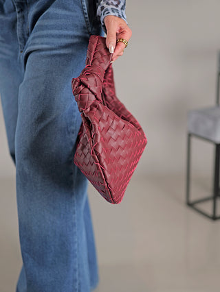 Eine Person hält die OFF#DLY Ledertasche Dagmar burgundy, eine geflochtene Echtledertasche mit Reißverschluss, in der Hand.