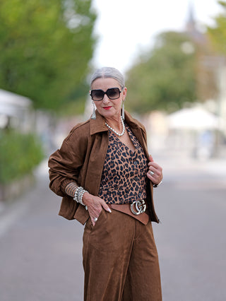 Frau trägt OFF#DLY Gitte Weste Leo mit Leopardenmuster und Sonnenbrille, über einem lässigen Kleid. Die Weste hat einen lockeren Schnitt, ideal für Streetwear-Looks.