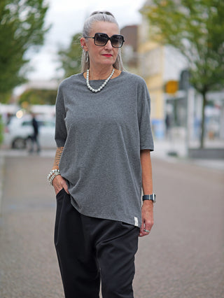 Frau trägt das Cotton Candy Tee Umut, ein weiches, langärmeliges Shirt mit O-Neck-Ausschnitt und grauem Melange-Muster, kombiniert mit einer Sonnenbrille.