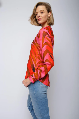 Emily Bluse rot pink zebra: Frau in bunter Shirtbluse mit Stehkragen, halber Knopfleiste und langen Ärmeln. Fließende Viskose mit auffälligem Zebra-Print. Model trägt Jeans.