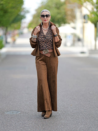 OFF#DLY Pant Clara: Frau trägt eine weite Velours-Optik-Hose mit seitlichen Einschubtaschen. Kombiniert mit einem Leopardenmuster-Oberteil und Sonnenbrille, präsentiert die Hose einen modischen Straßenlook.