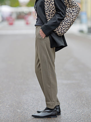 OFF#DLY Pant Clara khaki, getragen von einer Person mit Gummibund und seitlichen Einschubtaschen, kombiniert mit einem auffälligen Leopardenmuster-Outfit und schwarzen Stiefeln.