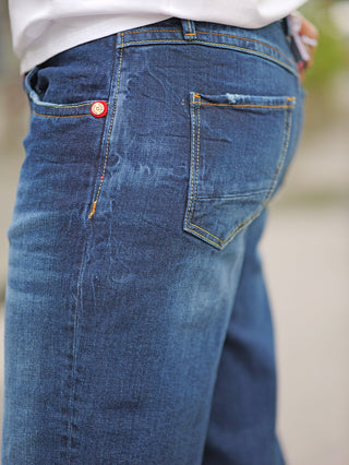 TAKE 2 Sendai Denim wide leg Jeans mit weitem Schnitt und gelber Naht, Nahaufnahme der Rückentasche und Knopfdetails, getragen von einer Person, zeigt die Midblue Waschung und 5-Pocket-Design.