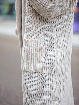Nahaufnahme der OFF#DLY Clara Strickjacke lang white, einer weißen langen Grobstrickjacke mit seitlichen Taschen, betont durch die sichtbare Struktur des gestrickten Materials.