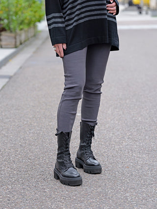 Person trägt OFF#DLY Legging Sonja grau, kombiniert mit schwarzen Boots. Die Leggings aus Viskose und Baumwolle wirkt bequem. Modelgröße 172cm, trägt Größe S/M.