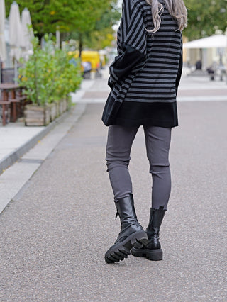 Person trägt OFF#DLY Legging Sonja grau, kombiniert mit schwarzen Stiefeln und gestreiftem Pullover. Die Leggings sind bequem, aus Viskose-Baumwoll-Mix, mit seitlichen Taschen.