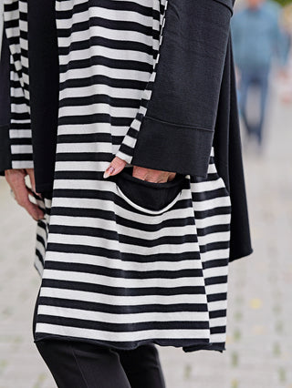 Philomena Jacke Streifen WL226: Person trägt eine lange, gestreifte Jacke ohne Knopfleiste mit seitlichen Taschen, betont durch modisches Design.