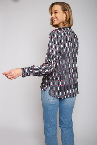 Emily Shirtbluse Fade out black/pink: Frau trägt eine geometrisch gemusterte Shirtbluse mit kleinem Kragen, V-Ausschnitt und langen Ärmeln, gefertigt aus Viskose Satin.