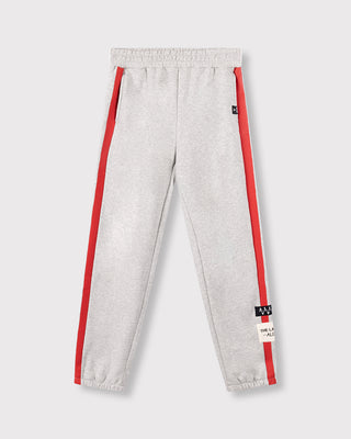 Alix Stripe Pants soft grey: Graue Jogginghose mit roten Streifen an den Seitennähten, elastischem Bund und ALIX-Aufnähern am Bein. Entspannte Passform mit Fronttaschen, ideal für einen bequemen Look.