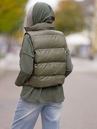 Frau trägt die OFF#DLY West Ronja khaki, eine kurze Steppweste mit Stehkragen und seitlichen Taschen. Perfekt für Street Fashion, passend in Größe S für 172 cm große Models.