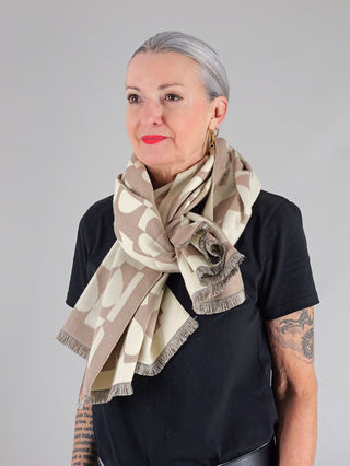 Eine Frau trägt den OFF#DLY Schal Heart beige um den Hals, der aus einem weichen Materialmix gefertigt ist und als modisches Accessoire dient.