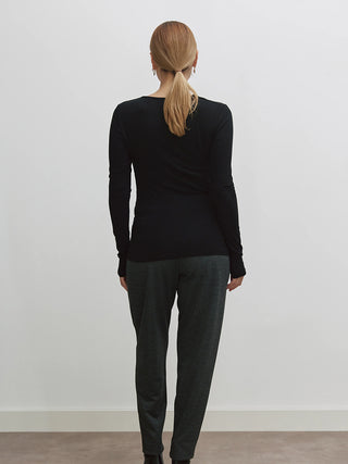 Frau trägt Cotton Candy Tee Liane black, ein enganliegendes Langarmshirt mit V-Ausschnitt und Raffung, das die Silhouette betont. Kombinierbar für elegante oder lässige Looks.