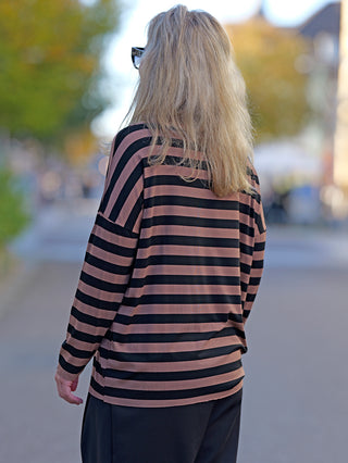 Frau trägt das OFF#DLY Ringel Grosso black/caramel, ein gestreiftes Shirt mit Rundhals und geschnittenen Kanten, ideal für lässige Street-Fashion. Perfekte Passform bis Größe 42.