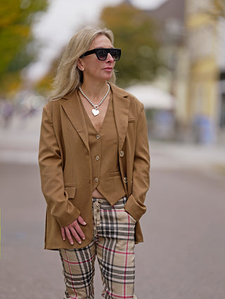 OFF#DLY Blazer Gianna camel: Frau trägt übergroßen, kastanienbraunen Blazer mit silberner Halskette und Sonnenbrille, seitliche Taschen und Knopfleiste sichtbar.