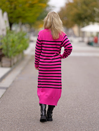 Frau im OFF#DLY Ringelkleid pink, ohne Taschen, läuft auf Gehweg. Kleid hat Rundhalsausschnitt und besteht aus Viskose und Nylon. Perfekt für Street Fashion.