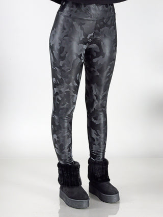Person trägt OFF#DLY camo Legging black mit schwarzen Stiefeln und einem schwarzen Pelzmantel. Die Leggings bestehen aus 100% Polyester und sind in einem enganliegenden Schnitt gestaltet.