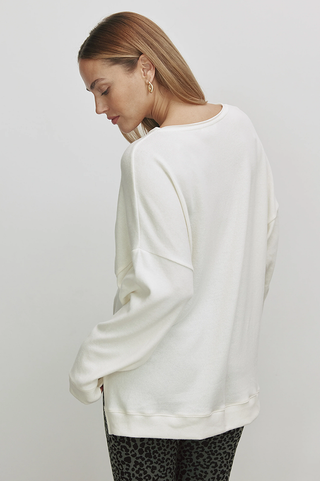 Frau trägt das Cotton Candy Irma Tee in Offwhite, ein superweiches, lässiges Langarmshirt mit Print MERRY EVERYTHING, oversized geschnitten. Perfekt für vielseitige Kombinationen im Alltag.