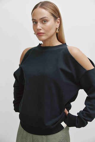Frau trägt das Cotton Candy Lisbeth Sweatshirt mit Rundhalsausschnitt und Metallic-Naht an der Schulter. Es hat Cut Details und ist ein lässiges, modisches Must-Have für Frauen.
