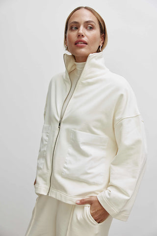 Frau trägt Cotton Candy Liz Sweat, eine weiße, oversized Sweatjacke mit Troyer Kragen und aufgesetzten Taschen, ideal für trendige Looks.