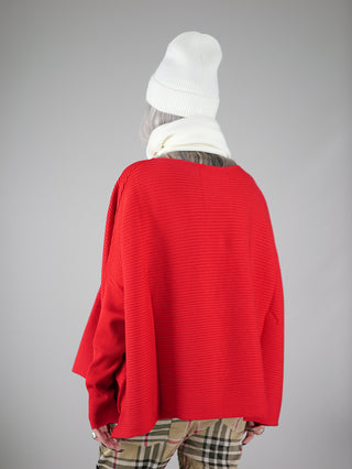 Person trägt Philomena Ripp Pulli FEAT rot, einen leichten, boxy geschnittenen Pullover. Sichtbar sind ein roter Pullover und eine weiße Mütze, die den modischen Look vervollständigen.