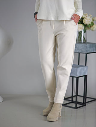 OFF#DLY Joggpant Doris beige: Person trägt beige Joggpant mit Bundfalten, Gummibund, Kordelzug und Aufschlag am Bein, kombiniert mit tan Boots.
