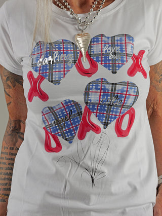 Frau trägt OFF#DLY Tee XOXO weiß/blau mit Herzdesign, kombiniert mit Halskette. Gerade Passform, ideal für lässige Anlässe. Baumwollmischung, Größe S/M abgebildet.