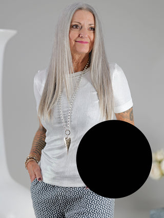 Frau mit langem grauen Haar trägt das OFF#DLY Top Sindy schwarz/silber, ein stylisches Feinripp-Top mit silbernem Lurex-Faden und Rundhalsausschnitt. Perfekt für Größen 34 bis 38/40.
