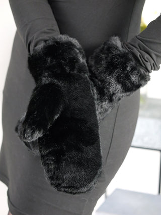 Person trägt OFF#DLY Handschuhe black, große schwarze Fäustlinge aus weichem Fakefur-Material.