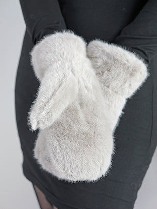 Eine Person trägt OFF#DLY Handschuhe grau, große, flauschige Fäustlinge aus Fakefur, die die Hände vollständig umschließen, mit einem separaten Daumenbereich. Hergestellt aus 100% Polyester.