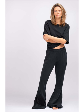 Frau mit verschränkten Armen trägt das True Religion Boxy Crew Tee in Schwarz. Das Shirt hat einen lockeren Schnitt und passt sich der Größe S an. Ideal für einen lässigen Look.