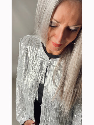 Frau mit langen Haaren trägt die OFF#DLY Jacke Olivia silber, eine kurze Jacke mit Zipper und Paillettenbesatz. Die Jacke hat eine gerade Passform und besteht aus 100% Polyester.