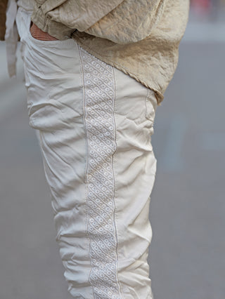 OFF#DLY Pant Olga champagner, schmale Joggpant mit seitlichem Brokat-Einsatz, sichtbar sind der Gummibund und Kordelzug, getragen von einer Person, zeigt feine Stoffstruktur und moderne Passform.