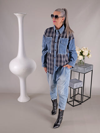 Frau trägt OFF#DLY Denimbluse Clara mit Karomuster, Knopfleiste und Brusttaschen, steht neben einem Blumenstrauß in einer Vase.