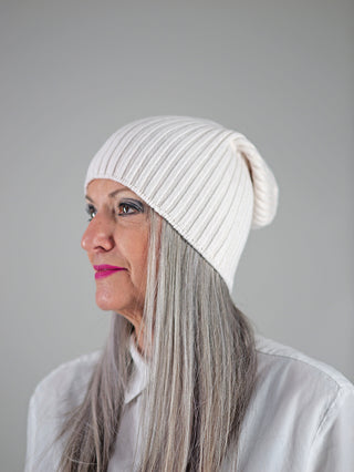 Frau trägt die OFF#DLY Mütze Anna creme, eine stilvolle weiße Beanie aus Viskosemix, die sanft das Gesicht umrahmt. Ideal für modische Akzente und angenehmen Tragekomfort.