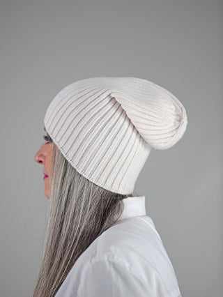Frau trägt die OFF#DLY Mütze Anna creme, eine weiße Beanie, die stilvoll den Kopf bedeckt. Die Mütze besteht aus Viskose, Polyester und Polyamid und ist modisch und elegant gestaltet.