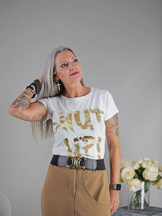 Frau mit Tattoos trägt OFF#DLY Tee Shut up, weißes Kurzarmshirt mit Shut up Print, neben einem Blumenstrauß in Glasvase. Perfekt für Größe 34 bis 38, gerader, schmaler Schnitt.