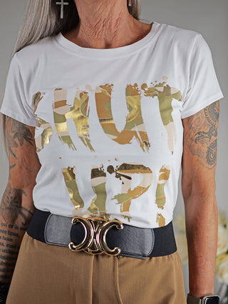 Frau trägt das OFF#DLY Tee Shut up weiß, mit goldfarbenem Textprint, kurzen Ärmeln und gerader Passform. Sichtbare Details: Gürtel, Tattoo am Arm, enganliegendes Design.