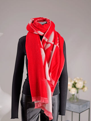 Schwarzer Mannequin mit einem leuchtend roten OFF#DLY Schal Adelina rot/weiß, kunstvoll um den Hals gewickelt, mit hellen Herzmotiven und Fransen, präsentiert in einem schlichten Studio mit Rosen im Hintergrund.