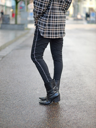 OFF#DLY Pant Tina black, getragen von einer Person, kombiniert mit einem karierten Hemd. Die Hose hat einen Gummibund, seitliche Kettenkordel und Taschen, passt gerade und normal.