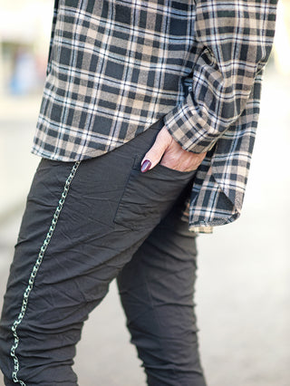OFF#DLY Pant Tina black: Leichte Joggpant mit seitlicher Kettenkordel, Gummibund, seitlichen Einschubtaschen. Person steckt Hand in die Hosentasche, zeigt Stoff und Design der Hose.
