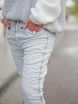 Eine Person trägt die OFF#DLY Pant Tina grey, eine leichte Joggpant mit Kettenkordel und seitlichen Taschen, sichtbar ist eine Hand in der Hosentasche mit einem Ring.