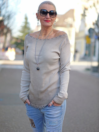 Frau trägt OFF#DLY LS Mila taupe Strick-Longsleeve mit Rundhals und Spitzeneinsatz, Hände in Taschen, kombiniert mit Sonnenbrille und Schmuck.