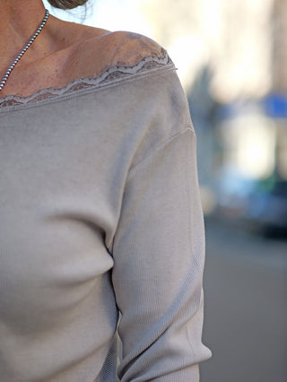 Nahaufnahme eines Shirts mit großem Rundhals und Spitzeneinsatz am Ausschnitt und Bund. Das Strick-Longsleeve OFF#DLY LS Mila taupe zeigt eine schmale, gerade Passform.